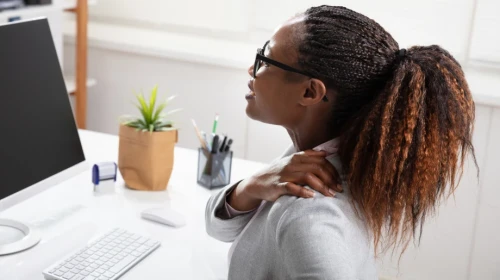 Woman Suffering from Rotator Cuff Injury from sitting at desk with computer