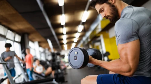 man at the gym doing biceps curls with dumbbells