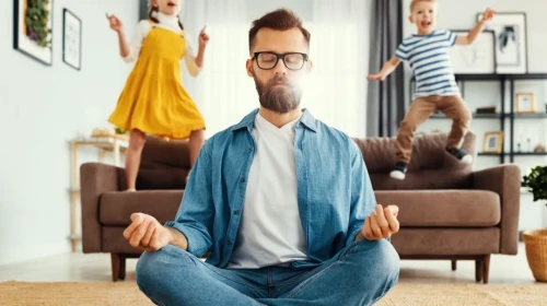 Man meditating and practicing yoga poses with children in the background
