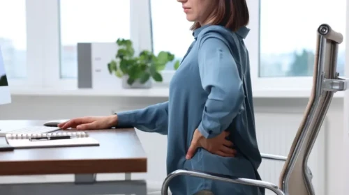 woman touching back and appearing in pain
