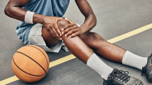 Athlete sitting on ground grabbing knee