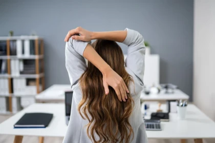 Woman sitting at a desk stretching | Stretching for Sore Shoulders