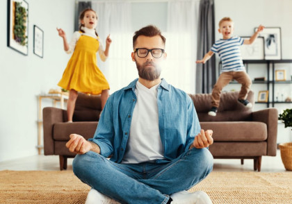 Man meditating and practicing yoga poses with children in the background