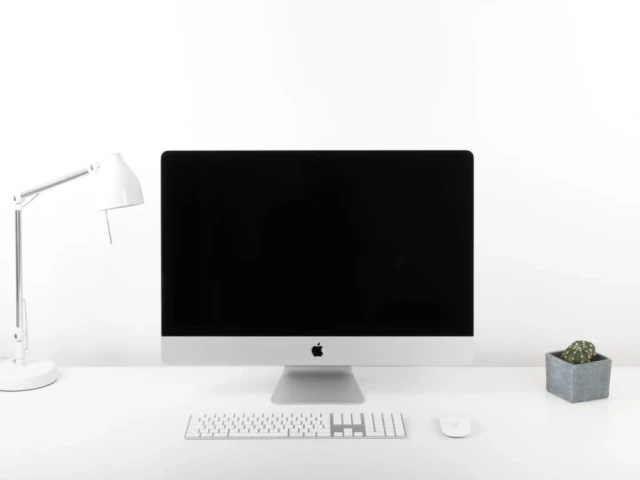 Apple computer on a desk with a lamp