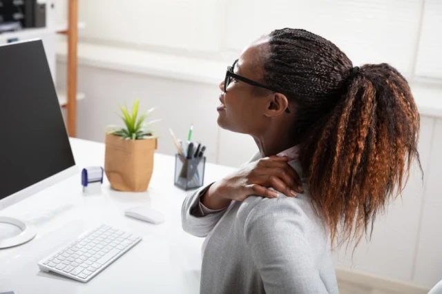 Woman Suffering from Rotator Cuff Injury from sitting at desk with computer