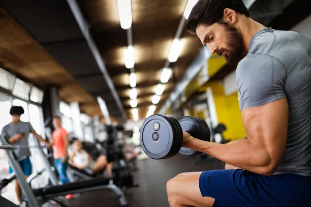 man at the gym doing biceps curls with dumbbells