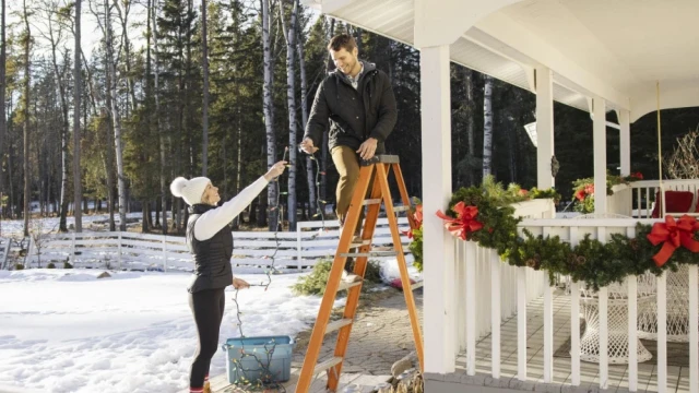 Couple Stringing Christmas Lights on Ladder