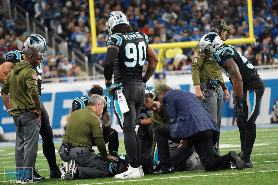 Dr. Pat Connor (blue jacket) evaluates a Carolina Panthers player on the field.