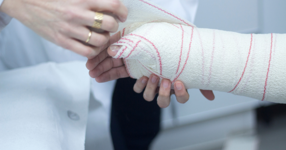 Doctor wrapping up wrist after hand fracture treatment.